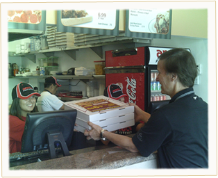 Our Ameci Team Member serving another happy customer hs pizzas.